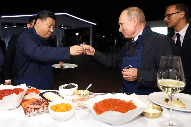 Le président Vladimir Poutine et son homologue chinois Xi Jinping mangent des crêpes russes à l'exposition Far East Street en marge du Forum économique de l'Est 2018 sur l'île de Russky, le 11 septembre